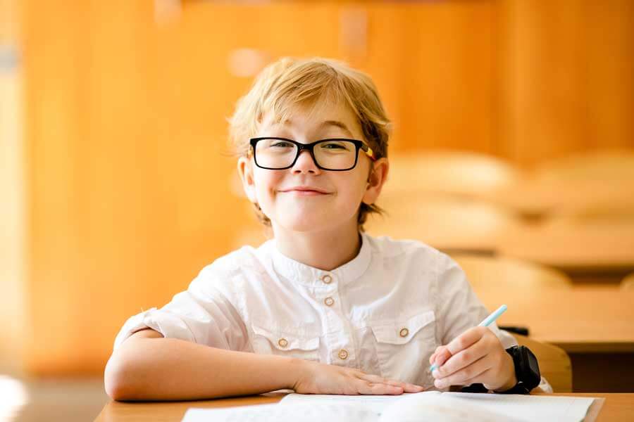 a boy smiling while studying at his desk